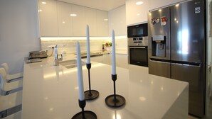 Eine moderne Küche mit weißen Schränken, einem Edelstahlkühlschrank und einer zentralen Kochinsel mit Kerzen.