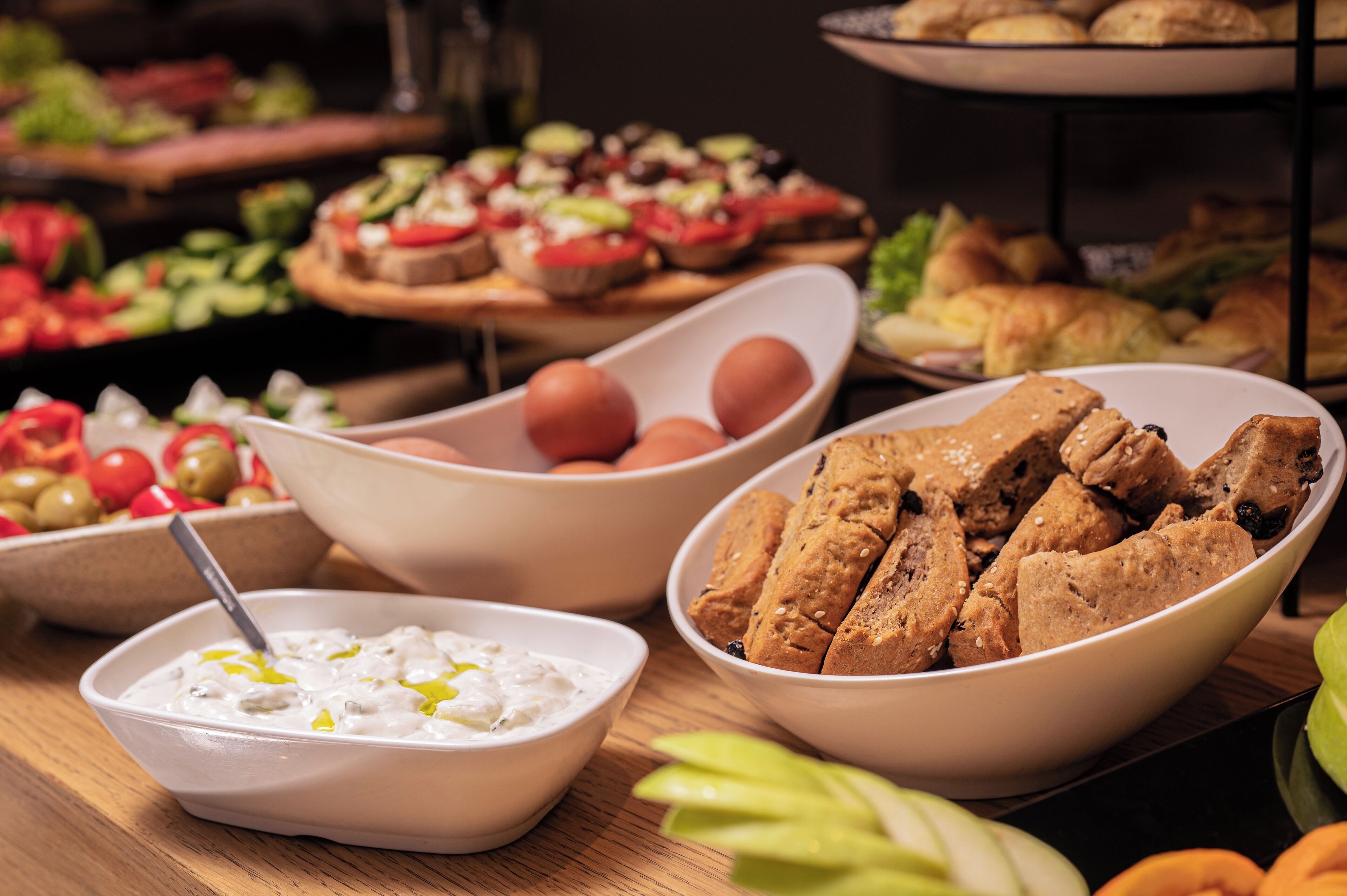 A buffet table with various food items including bowls of dips, bread, and vegetables.