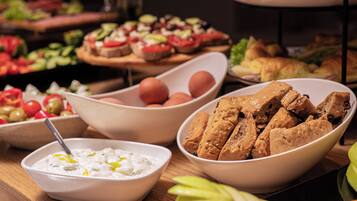 A buffet table with various food items including bowls of dips, bread, and vegetables.