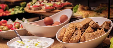 A buffet table with various food items including bowls of dips, bread, and vegetables.