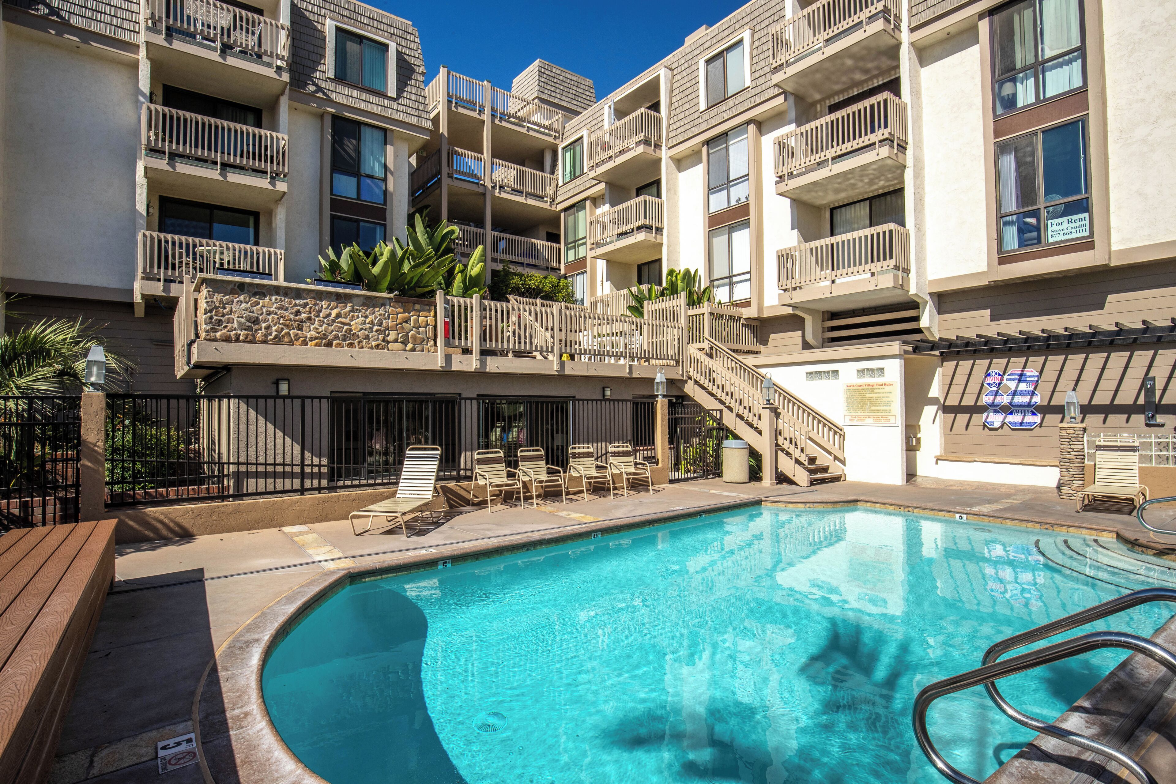 A pool area with lounge chairs and a stone wall.