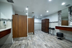 A modern bathroom with a wooden partition, a large mirror, and a bar stool.