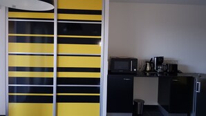Eine moderne Küche mit einer schwarz-gelb gestreiften Tür, einer Mikrowelle, einer Kaffeemaschine und einem Kühlschrank.
