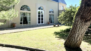 A building with large arched windows, a flat roof, and a gravel driveway. - Villa Piscine Ardèche (Rochemaure)