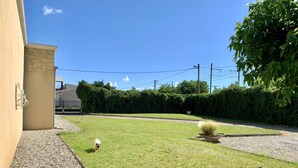 A well-maintained lawn with a small dog, a gravel path, and a hedge in the background. - Villa Piscine Ardèche (Rochemaure)