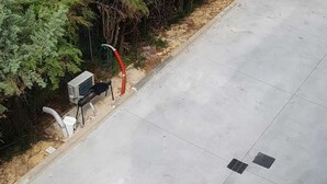 Una superficie pavimentada con una rejilla de desagüe y un carretel de manguera.