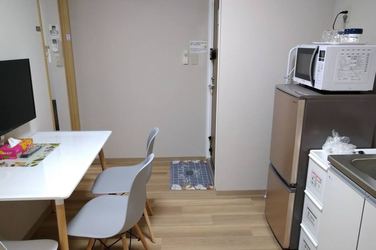 A compact kitchen with a microwave, refrigerator, and a small dining area with chairs and a table.