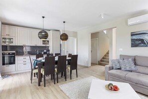 Un appartement moderne comprenant une cuisine, un coin repas et un salon. Il est équipé d’un escalier, d’un canapé et d’une table basse.