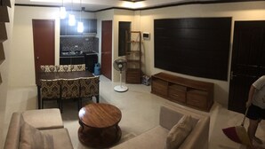 A living room with a dining table, sofas, a coffee table, a TV, and a fan. - Your Home Away From Home (Talisay)