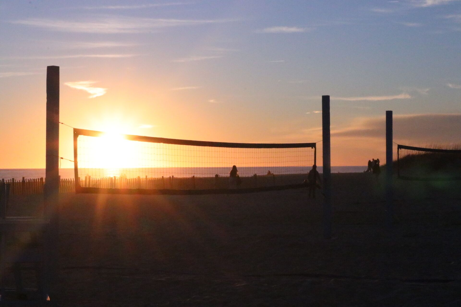 Ein Beachvolleyballfeld bei Sonnenuntergang mit Netz und Pfosten.