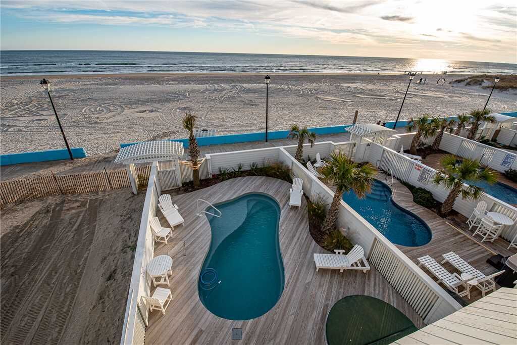 A pool area with multiple pools, lounge chairs, and a view of the beach.