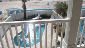 A balcony with a pool, overlooking a beach with a fence and chairs. - Ocean Front Ocean View, With Private Heated Pool & Hot Tub (Atlantic Beach)