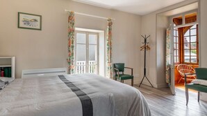 Una camera da letto con un letto, una sedia, un appendiabiti e una finestra con tende.