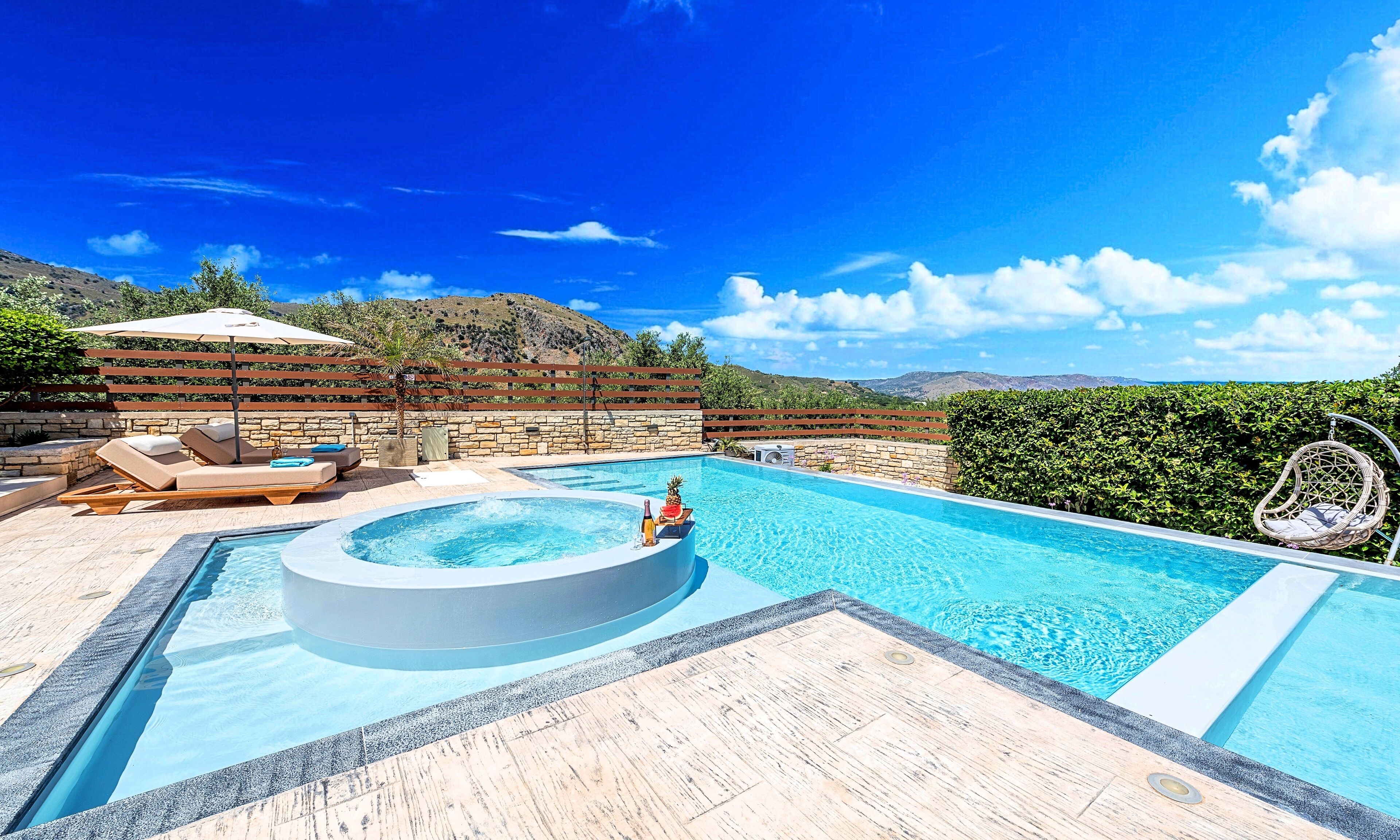 Une piscine avec un jacuzzi, des chaises longues et une terrasse en bois.