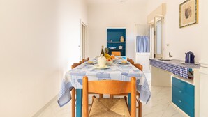 A dining area with a checkered tablecloth, wooden chairs, a blue cabinet, and a kitchen counter.