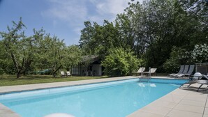 Une piscine à l’eau d’un bleu cristallin, entourée d’une terrasse carrelée et de chaises longues.