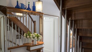 Un escalier en bois avec un vase blanc rempli de fleurs sur la plateforme.