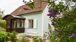 Une maison bleu clair avec un toit en pente, des volets blancs et un banc à l’extérieur.