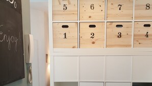 A storage unit with numbered compartments, a wall-mounted telephone, and a chalkboard with 'Enjoy!' written on it. - Apartment with garden + free parking lot -T1 (Wien)