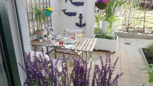 A wooden table set with breakfast items, a white wall with nautical decorations, and potted plants. - Apartment with garden + free parking lot -T1 (Wien)