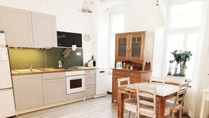 A kitchen with wooden cabinets, a dining table, and chairs. - Apartment with garden + free parking lot -T1 (Wien)