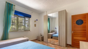 Un dormitorio con dos camas, un armario, un espejo y una ventana con cortinas.