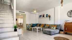 Un salon moderne avec un escalier, un ensemble de canapés, une table basse et un meuble en bois.