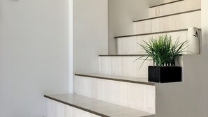 Un escalier avec des marches blanches et un pot de fleurs placé sur le palier.