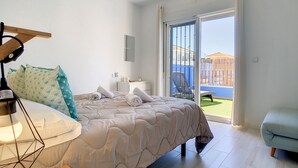 Une chambre à coucher avec un lit, un bureau, une chaise et un balcon offrant une vue.