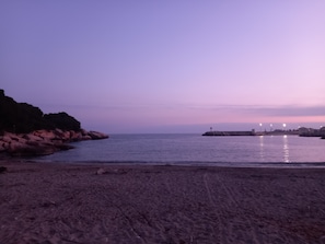 A beach with rocky terrain and calm waters.