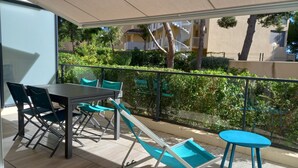Un balcon avec une table et des chaises, une chaise bleue et un tabouret bleu.