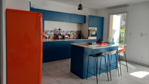 Une cuisine moderne avec des meubles bleus, un plan de travail blanc et un réfrigérateur rouge.
