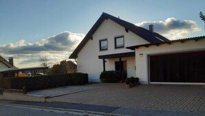 A two-story house with a garage, a paved driveway, and a well-maintained lawn. - Large, spacious vacation apartment in Ebermannsdorf (Ebermannsdorf)
