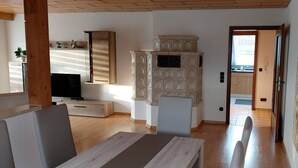 A room with a wooden floor, a TV, a cabinet, and a door leading to a kitchen. - Large, spacious vacation apartment in Ebermannsdorf (Ebermannsdorf)