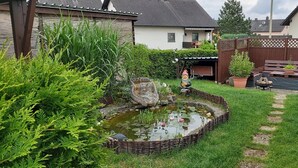 A garden with a pond, wooden fence, and a bench. - Large, spacious vacation apartment in Ebermannsdorf (Ebermannsdorf)