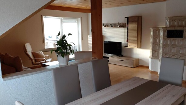 A modern living room with a wooden TV stand, a large cabinet, and a dining area with a table and chairs. - Large, spacious vacation apartment in Ebermannsdorf (Ebermannsdorf)