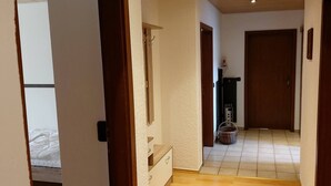A narrow hallway with wooden doors, a small shelf with a decorative item, and a tiled floor. - Large, spacious vacation apartment in Ebermannsdorf (Ebermannsdorf)