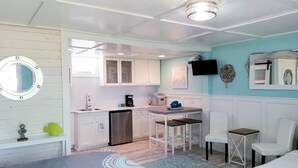 A compact room with a bed, a desk, a chair, a small table, a sink, and a microwave. - Cozy Studio Condo, short walk to Downtown Saugatuck, courtyard water view (Saugatuck)