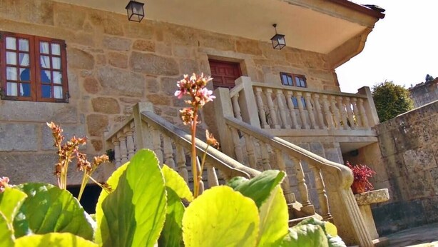 Ein Gebäude aus Stein mit Balkon, Treppe und Blumentöpfen.