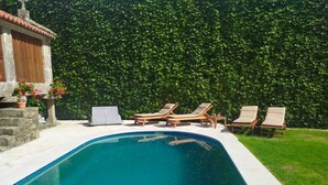 Ein Schwimmbecken mit Liegestühlen und einer Steinmauer.