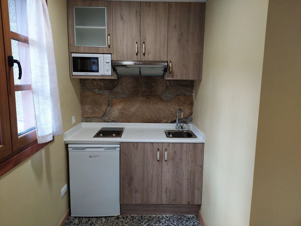 A compact kitchen with a dishwasher, a microwave, and a sink.