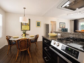 A modern kitchen with a dining area, featuring a stove, oven, and dining table with chairs.