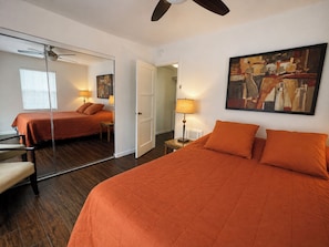 A hotel room with a large bed, a mirror, a painting, and a ceiling fan. - La Jolla Shores Modern Flat (La Jolla)