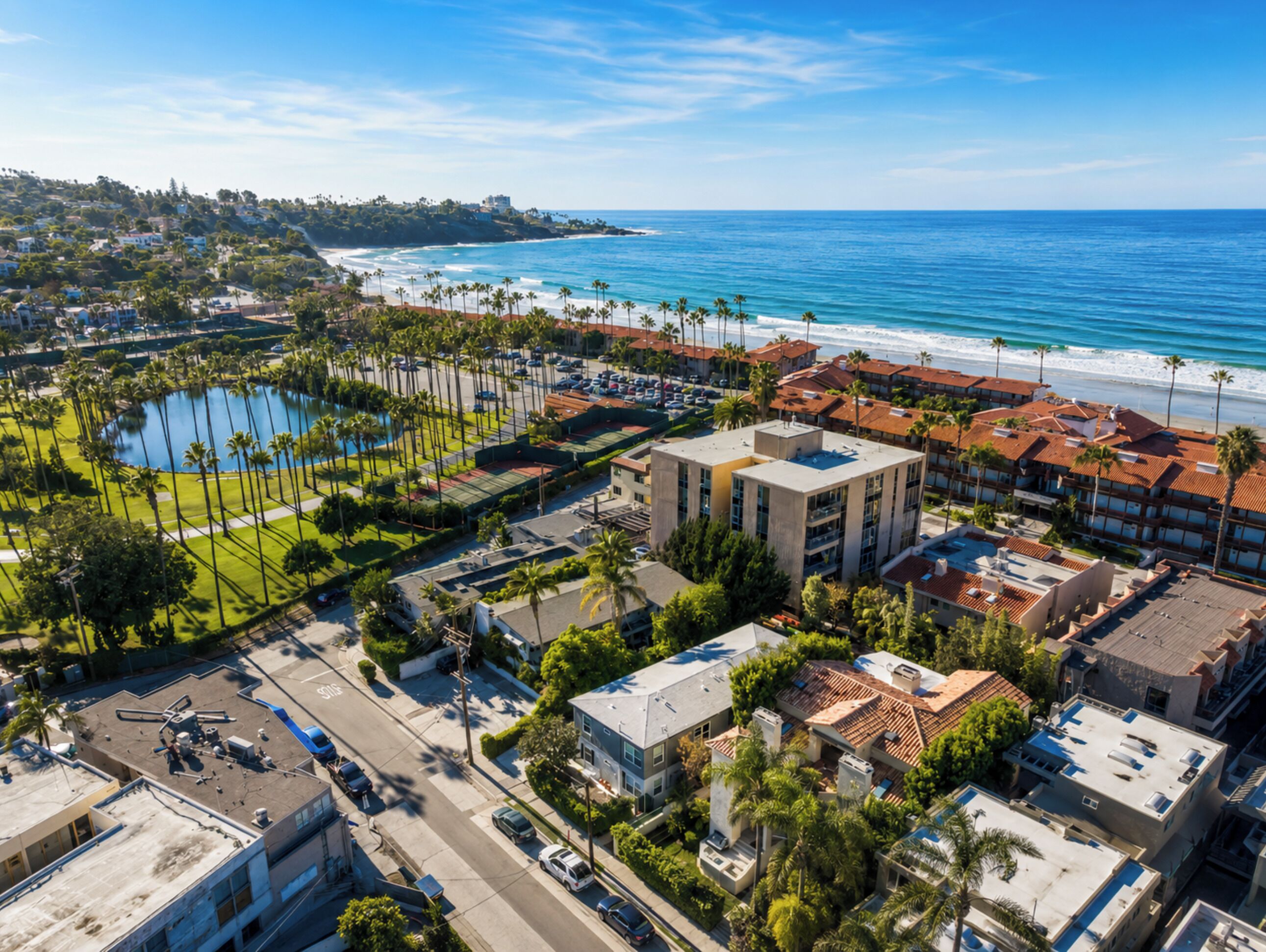 An aerial view of a coastal area with a hotel, a swimming pool, and a beach.