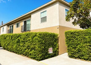 A two-story building with a beige exterior, a balcony on the second floor, and a sign indicating parking restrictions.