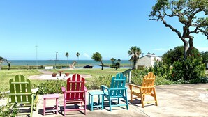 A patio with colorful Adirondack chairs facing a scenic ocean view. - The Sand Piper-Pier, Pool, Bay View & Boat Launch (Rockport)