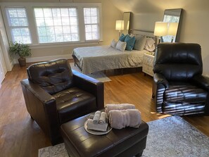 A bedroom with a bed, two black leather chairs, a nightstand, a lamp, and a potted plant. - Greenville Classic House. 4 bdrm, 3 bath. Walk to Ecu sporting events. Dogs ok (Greenville)