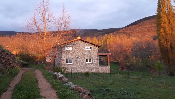 A stone house with a small porch, a stone wall, and a path leading to it. - CASA SIERRA AVELLANEDA AVILA SPAIN (Avellaneda)