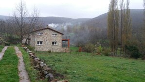 A stone house with a stone pathway leading to it, surrounded by a grassy field and trees. - CASA SIERRA AVELLANEDA AVILA SPAIN (Avellaneda)