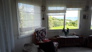 A living room with a sofa, a chair, and a view of greenery outside. - HOLIDAY HOUSE WITH STUNNING SEA VIEWS (Locquirec)